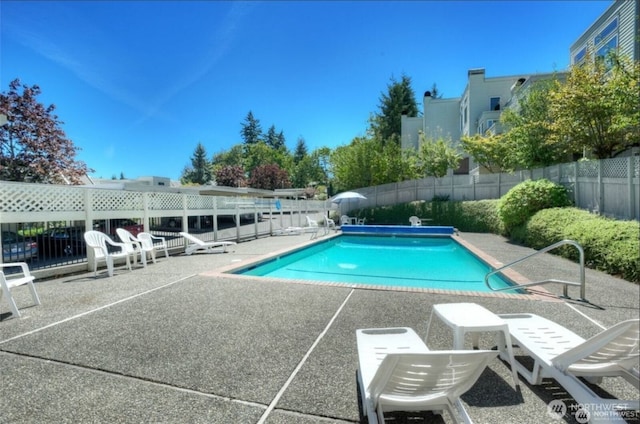 community pool with fence and a patio area