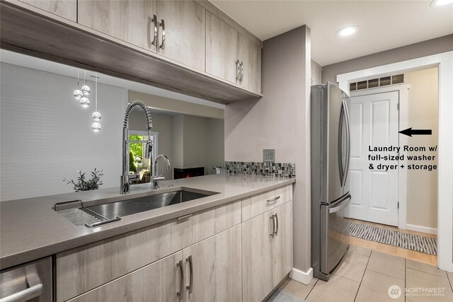 kitchen featuring freestanding refrigerator, a sink, light brown cabinets, light tile patterned floors, and recessed lighting