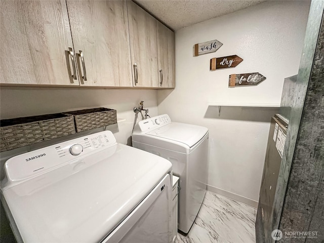 laundry area with cabinet space, washer and dryer, light marble finish flooring, baseboards, and a textured ceiling