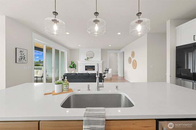5411 Lonicera Dr, Blaine, WA 98230 - kitchen with a sink, open floor plan, light countertops, a lit fireplace, and decorative light fixtures