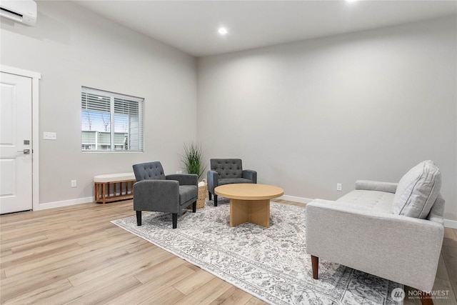 sitting room featuring a wall mounted air conditioner, wood finished floors, recessed lighting, and baseboards