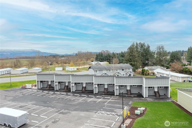 exterior space featuring a mountain view, a yard, uncovered parking, and community garages