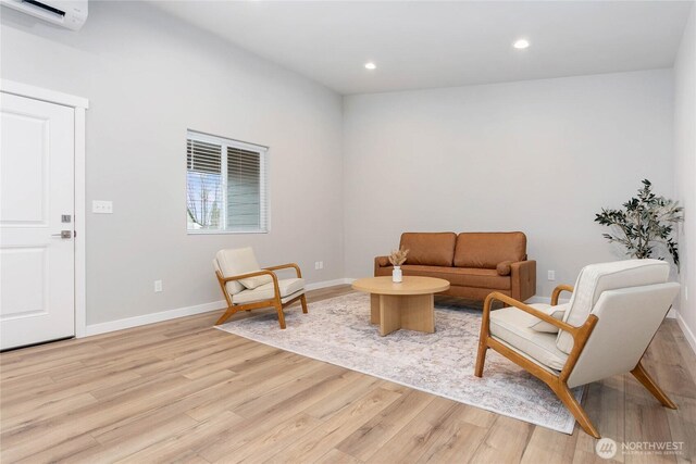 living room with light wood-style flooring, an AC wall unit, baseboards, and recessed lighting