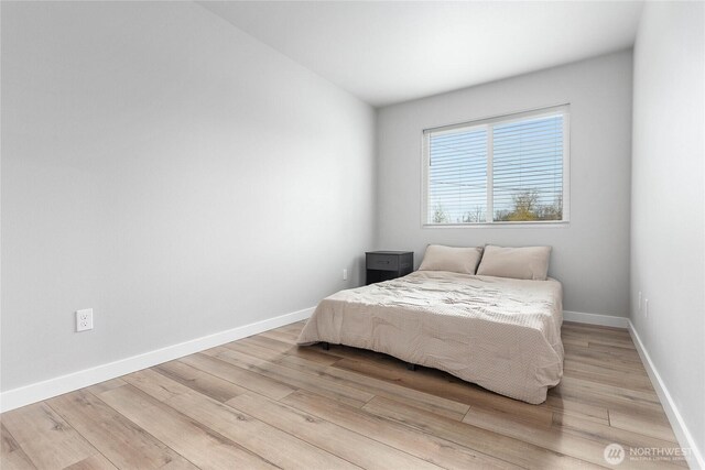 bedroom with light wood finished floors and baseboards