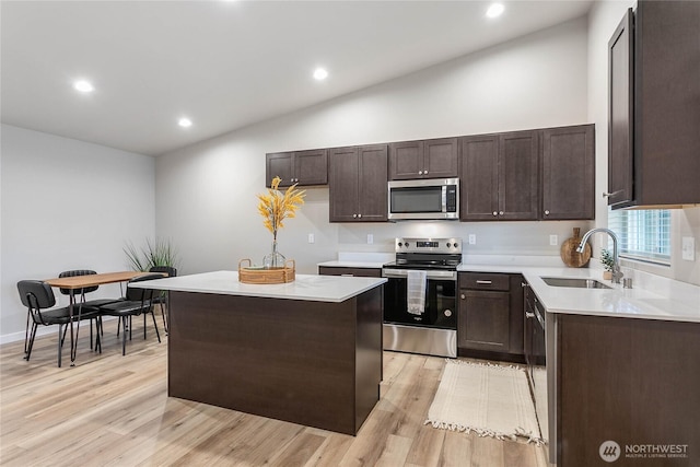kitchen with stainless steel appliances, a sink, light wood-style floors, dark brown cabinetry, and recessed lighting