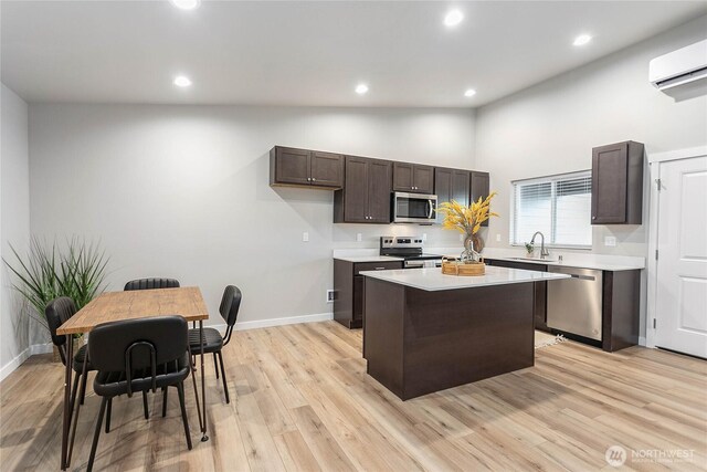kitchen with appliances with stainless steel finishes, an AC wall unit, dark brown cabinetry, a sink, and recessed lighting