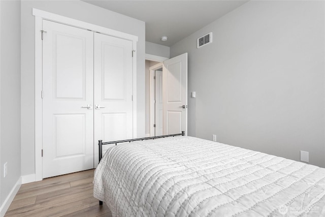 bedroom with light wood finished floors, a closet, and baseboards