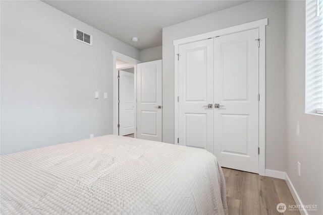 bedroom featuring light wood-style flooring, a closet, and baseboards