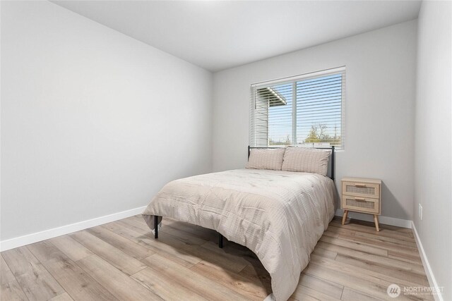 bedroom featuring light wood finished floors and baseboards