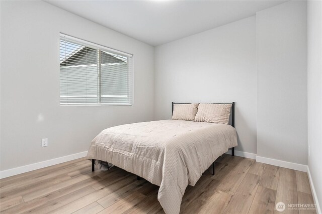bedroom with light wood finished floors and baseboards