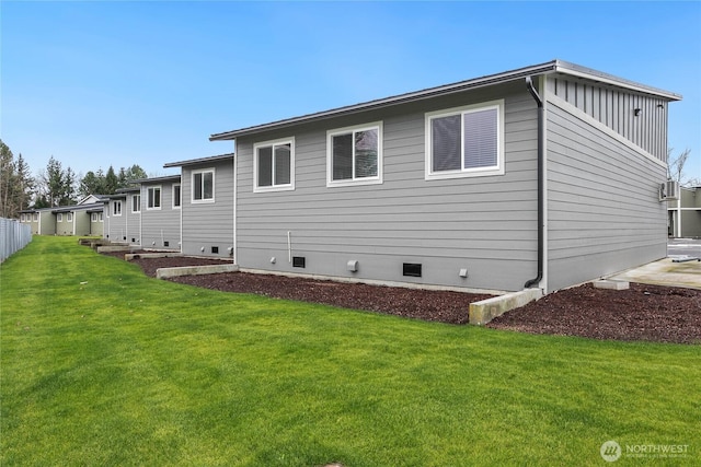 rear view of property featuring a yard, crawl space, and board and batten siding