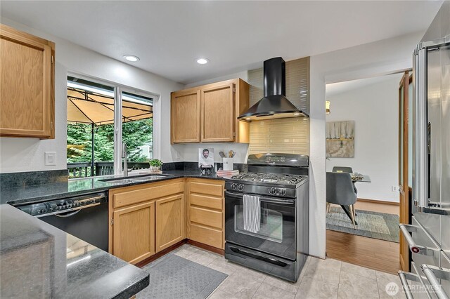 kitchen featuring black appliances, wall chimney range hood, a sink, dark stone countertops, and recessed lighting