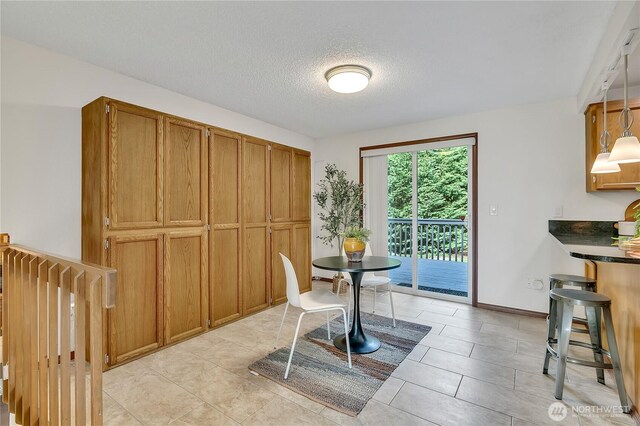 dining room with a textured ceiling, light tile patterned floors, and baseboards