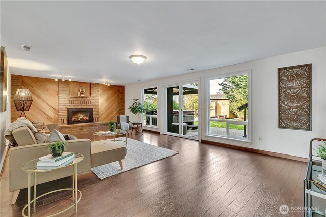 living room featuring wood walls, a fireplace, wood finished floors, and baseboards