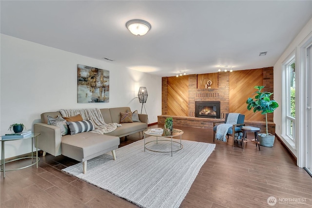 living area featuring wooden walls, a fireplace, and wood finished floors