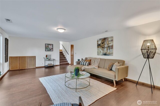 living room with stairs, wood finished floors, and baseboards