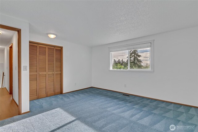 unfurnished bedroom featuring carpet flooring, baseboards, a textured ceiling, and a closet