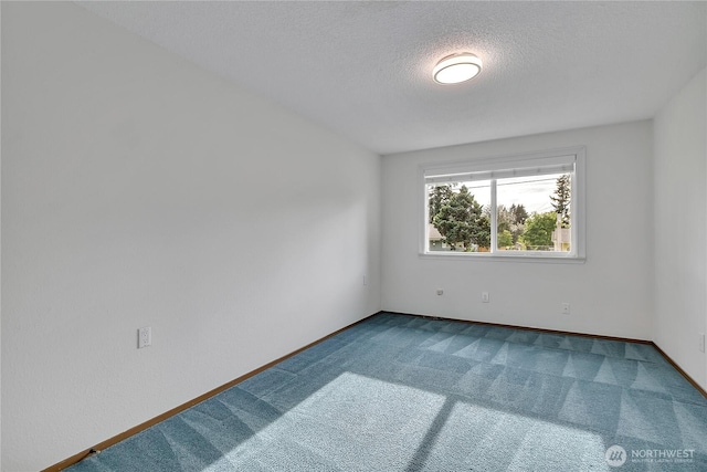 carpeted spare room with a textured ceiling and baseboards