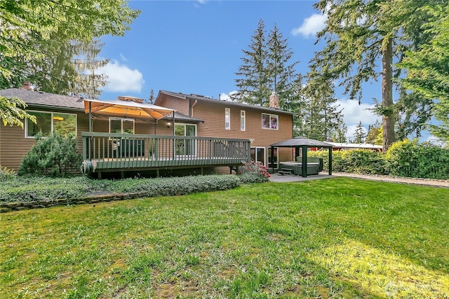 rear view of property featuring a gazebo, a hot tub, a chimney, a wooden deck, and a yard