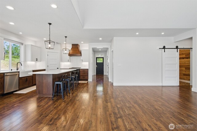 kitchen with dishwasher, premium range hood, a center island, light countertops, and dark wood finished floors