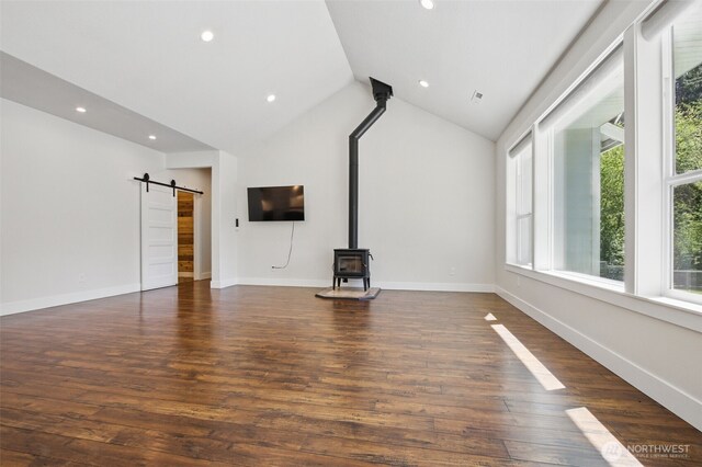 unfurnished living room with a barn door, a wood stove, dark wood finished floors, recessed lighting, and baseboards