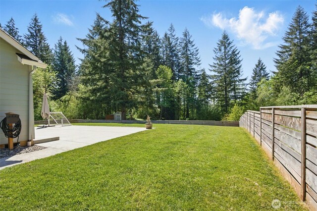 view of yard with a patio area, view of scattered trees, and an outbuilding