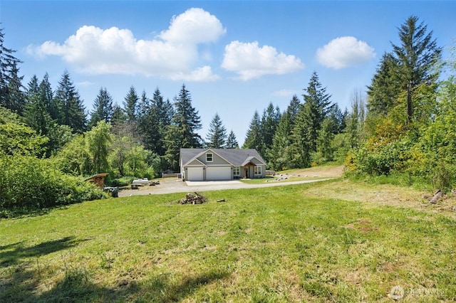 view of green lawn featuring an attached garage, driveway, and a view of trees