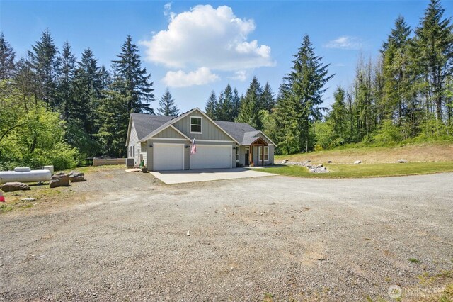 view of front of house featuring board and batten siding, dirt driveway, and a garage