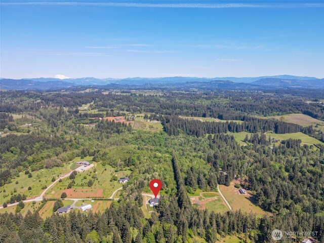 aerial view of property and surrounding area with a forest and a mountain backdrop