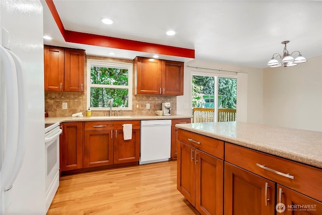 kitchen with white appliances, a sink, light wood-style floors, light countertops, and brown cabinets