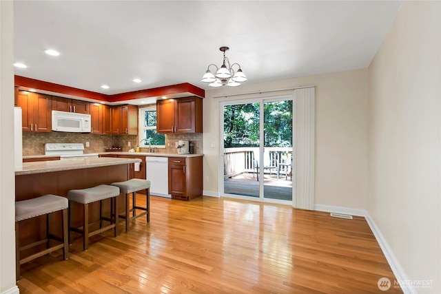 kitchen featuring white appliances, light wood-type flooring, backsplash, light countertops, and recessed lighting