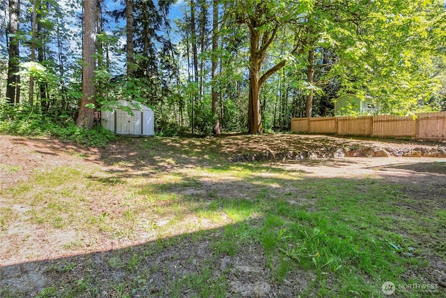 view of yard with a shed, fence, and an outbuilding
