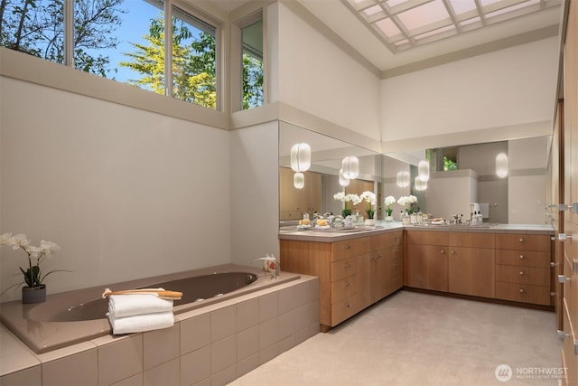 full bath with a garden tub, vanity, and a towering ceiling