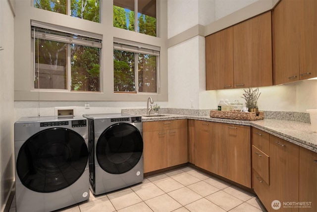 laundry area featuring washer and clothes dryer, light tile patterned floors, a high ceiling, and cabinet space