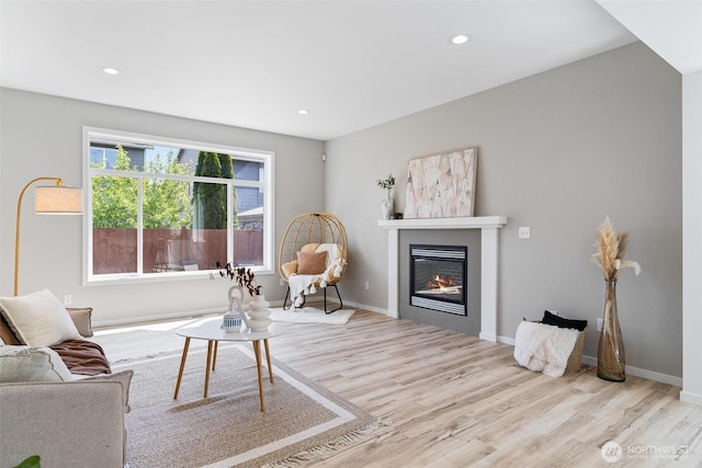 living room with wood finished floors, a fireplace, recessed lighting, and baseboards
