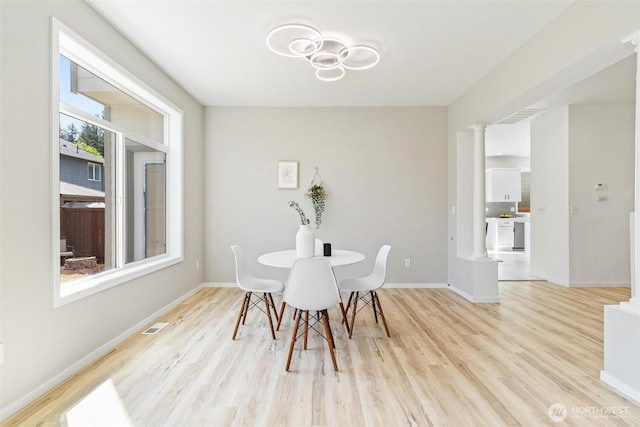 dining room with light wood-type flooring, baseboards, and decorative columns