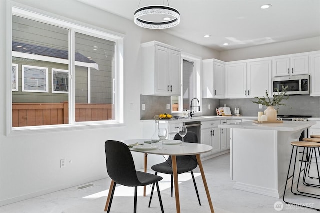 kitchen featuring appliances with stainless steel finishes, a sink, white cabinetry, backsplash, and recessed lighting