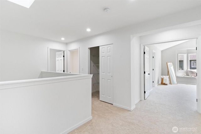 hallway featuring light carpet, baseboards, and recessed lighting