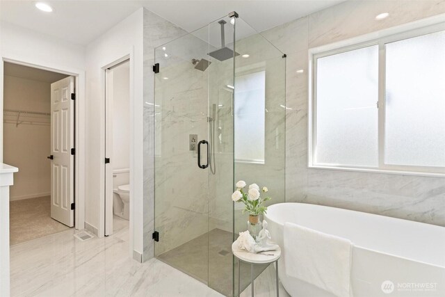 bathroom with a shower stall, marble finish floors, a freestanding tub, toilet, and a walk in closet