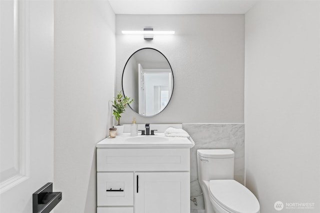 bathroom featuring vanity, toilet, and tile walls