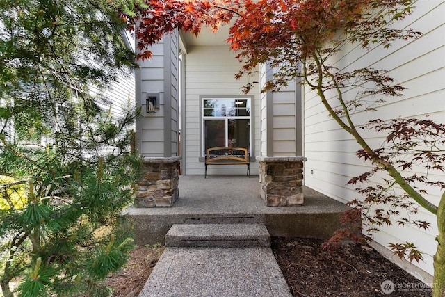 doorway to property featuring covered porch and stone siding