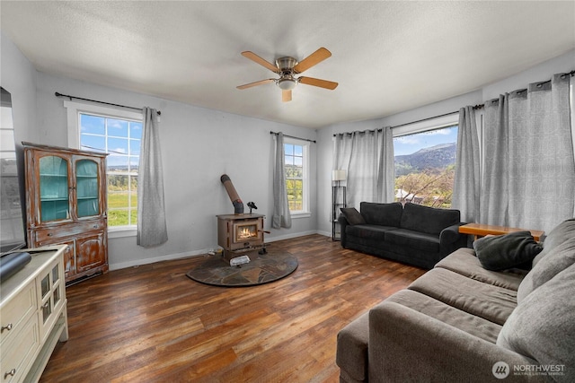 121 Temple Rd, Morton, WA 98356 - living room with a wood stove, baseboards, wood finished floors, a ceiling fan, and a textured ceiling