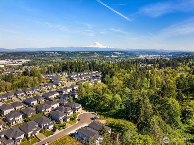 aerial view of property's location with a mountain backdrop, a forest, and nearby suburban area