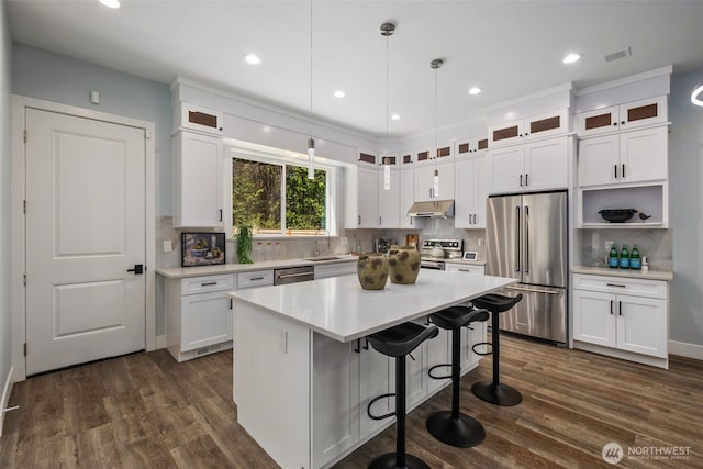 kitchen with appliances with stainless steel finishes, under cabinet range hood, tasteful backsplash, white cabinetry, and recessed lighting