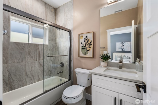 bathroom with vanity, bath / shower combo with glass door, and toilet
