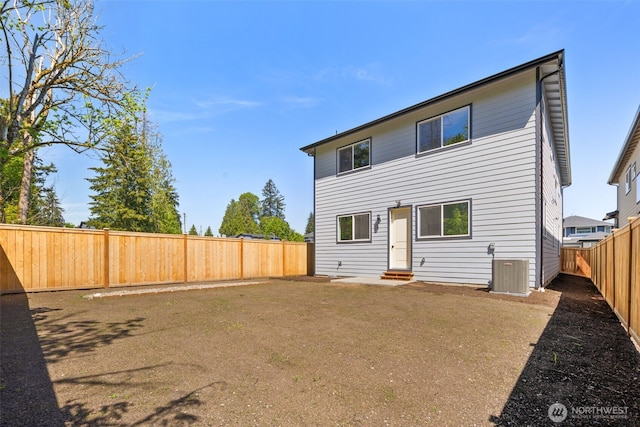 rear view of house with a fenced backyard and central AC
