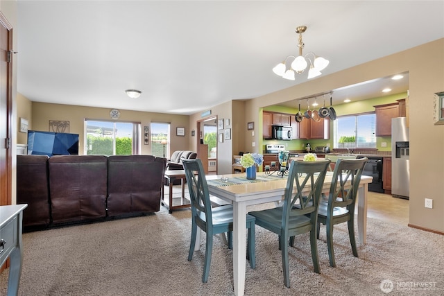 dining space featuring a chandelier, plenty of natural light, and light colored carpet