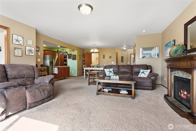 living room with light carpet, a chandelier, and a glass covered fireplace