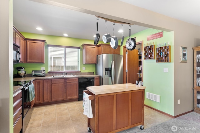 kitchen featuring black appliances, a sink, a center island, butcher block counters, and light tile patterned floors