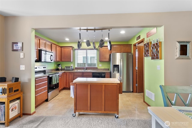 kitchen with stainless steel appliances, a sink, a kitchen island, hanging light fixtures, and light tile patterned flooring